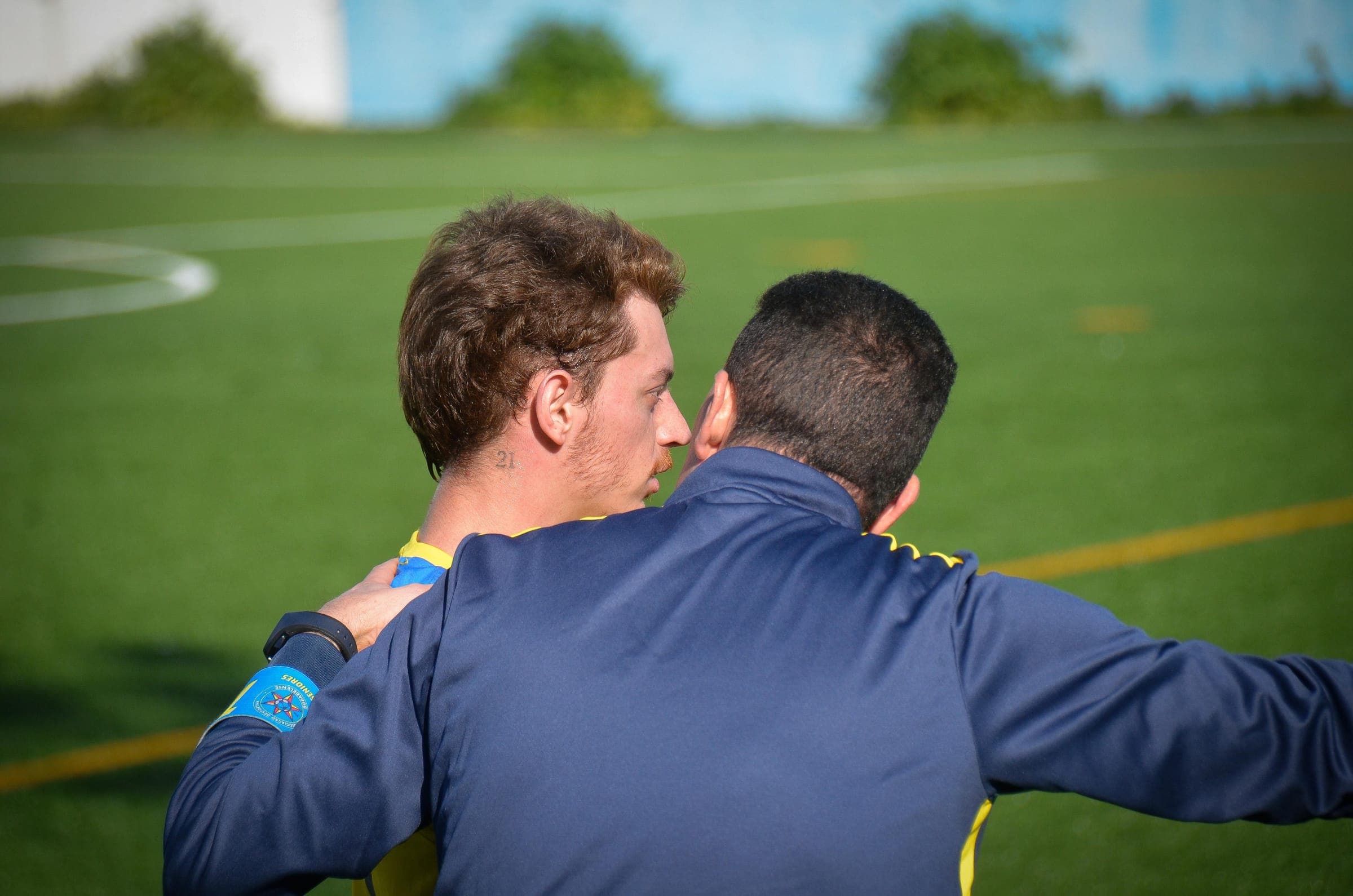 Coach with an arm around a player on the touchline